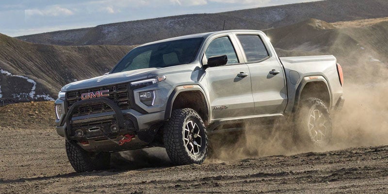 2026 GMC Canyon AT4X driving through rugged desert terrain